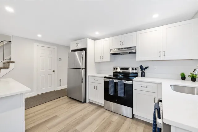 a kitchen with stainless steel appliances white cabinets and wooden floors