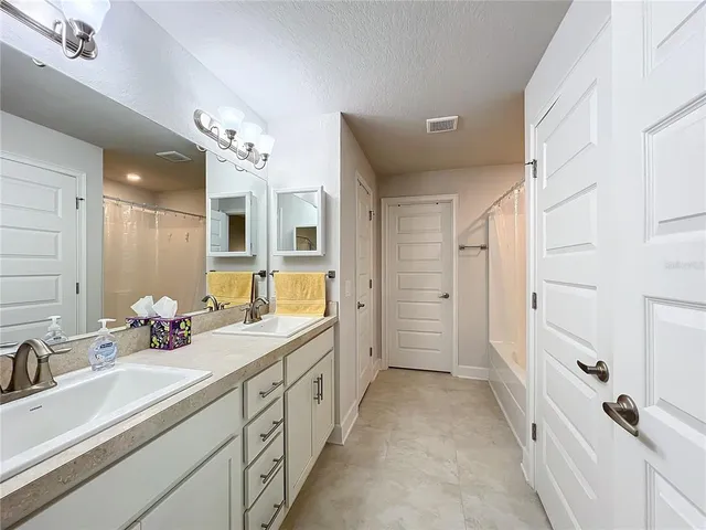 a spacious bathroom with a double vanity sink mirror and shower