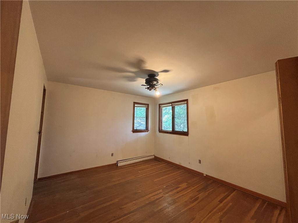 4912 Hillside Road Independence, OH 44131 - Photo 12 of 20 Empty room featuring dark wood-type flooring, a ceiling fan, and a baseboard heating unit