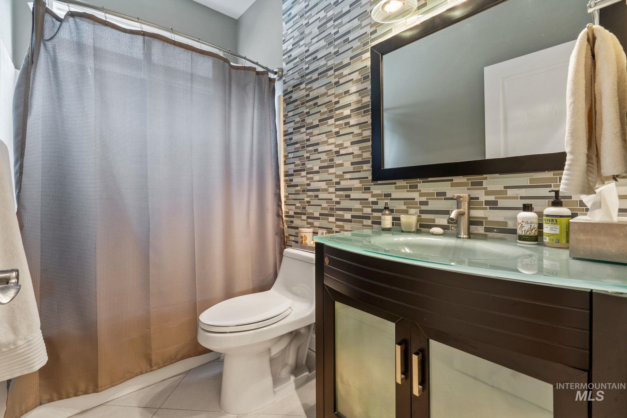 4235 Trekker Rim Drive East Boise, ID 83716 - Photo 14 of 33 Bathroom featuring vanity, light tile patterned floors, curtained shower, and decorative backsplash