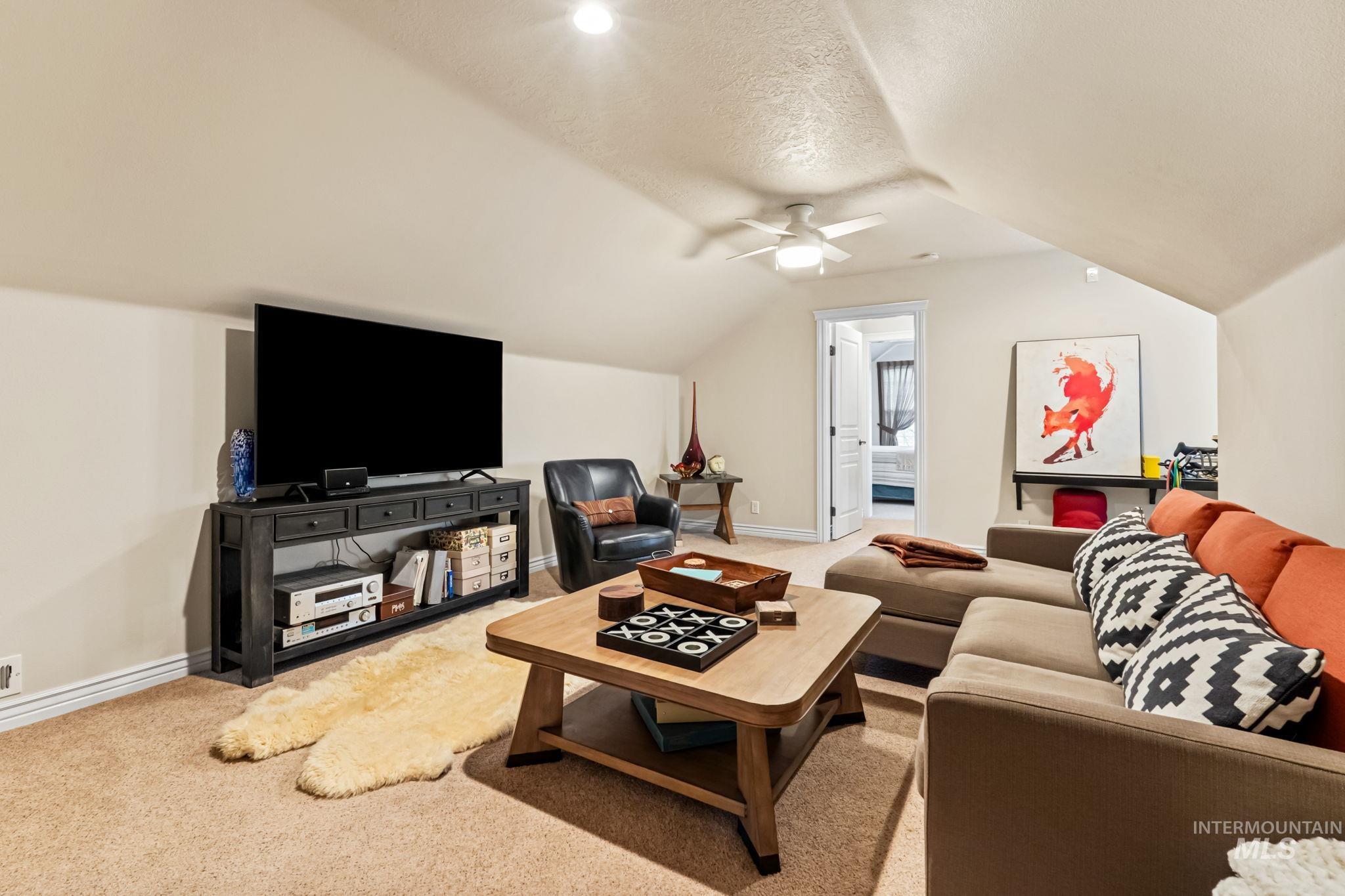 4235 Trekker Rim Drive East Boise, ID 83716 - Photo 19 of 33 Living area featuring light colored carpet, vaulted ceiling, a textured ceiling, and a ceiling fan