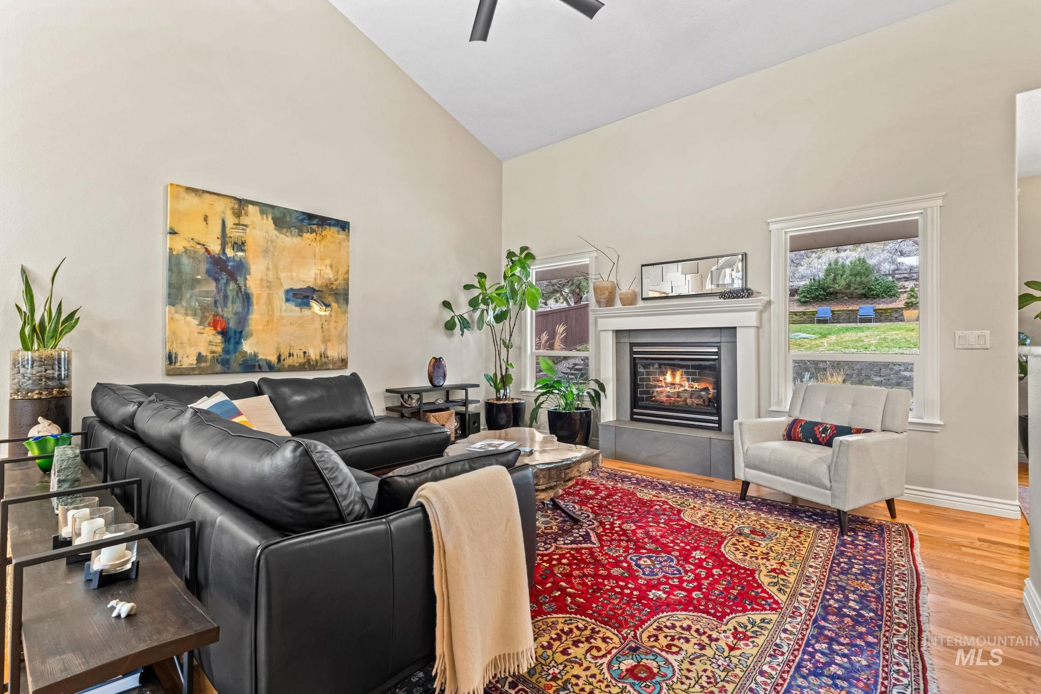 4235 Trekker Rim Drive East Boise, ID 83716 - Photo 5 of 33 Living area with high vaulted ceiling, a glass covered fireplace, light wood-style floors, and a ceiling fan