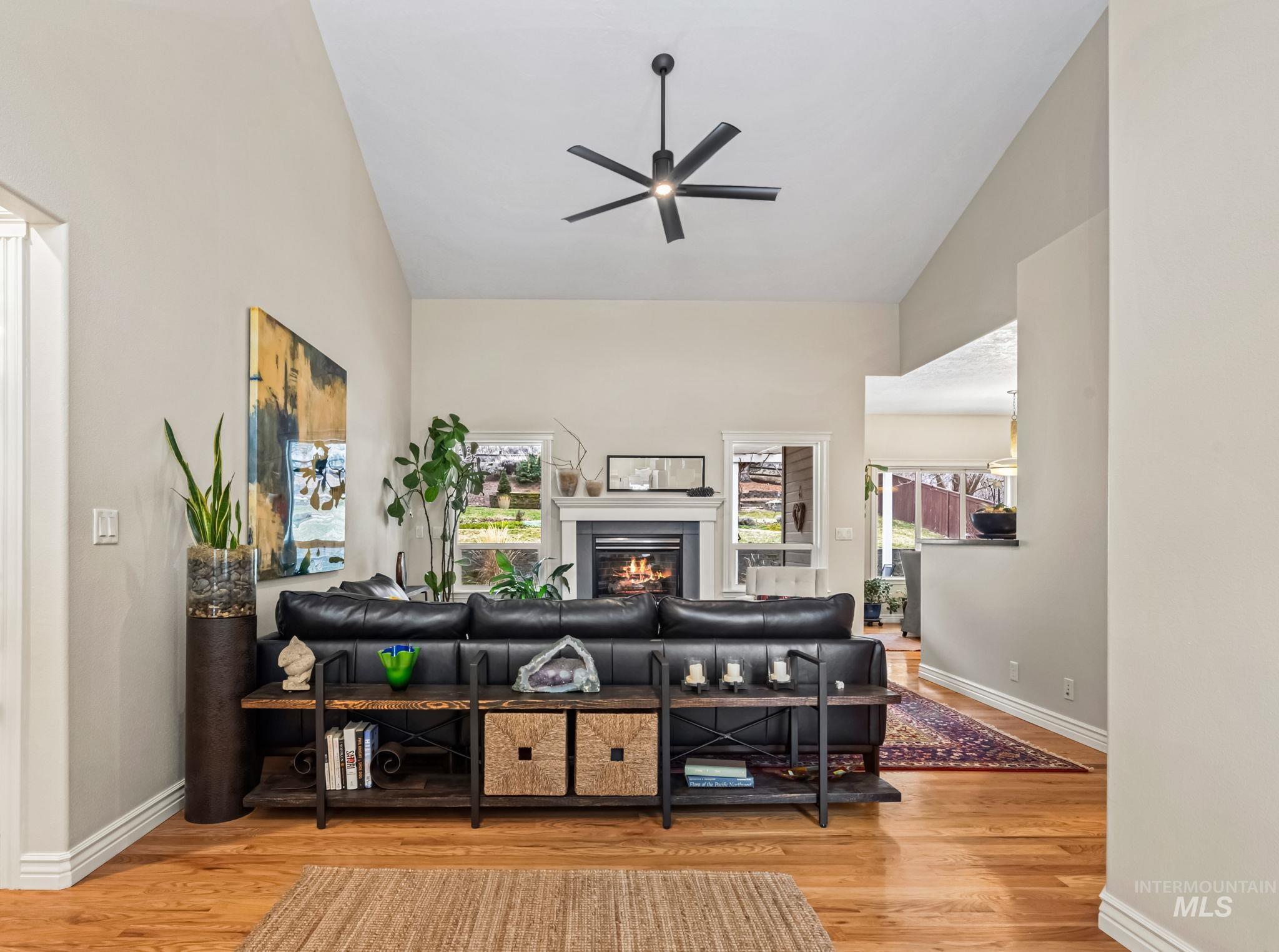 4235 Trekker Rim Drive East Boise, ID 83716 - Photo 6 of 33 Living room featuring vaulted ceiling, a warm lit fireplace, light wood finished floors, and ceiling fan