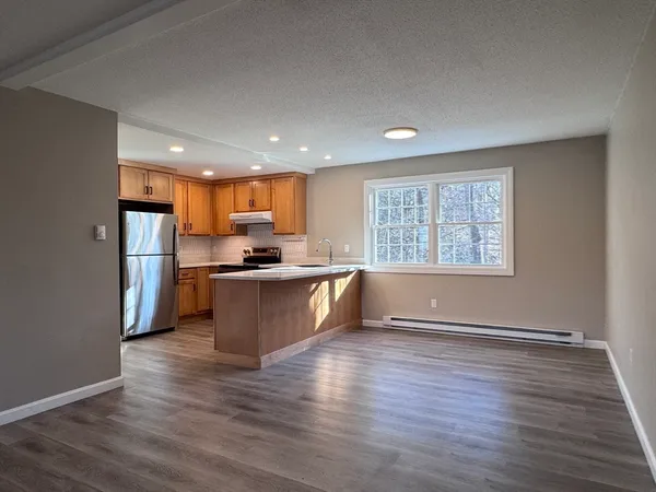 a kitchen with stainless steel appliances granite countertop a refrigerator a sink dishwasher a stove and a wooden floors