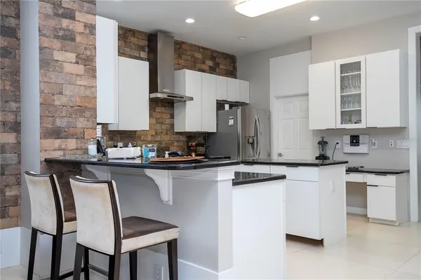 a kitchen with stainless steel appliances granite countertop a stove top oven a sink a refrigerator and white cabinets with wooden floor