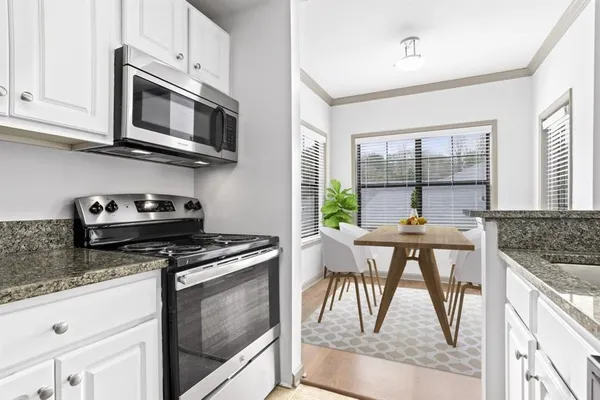 a kitchen with stainless steel appliances granite countertop a stove a microwave a sink and white cabinets