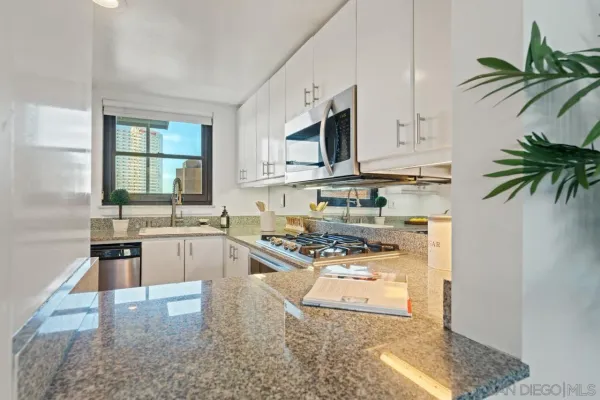 a kitchen with stainless steel appliances granite countertop a stove a sink and a white cabinets