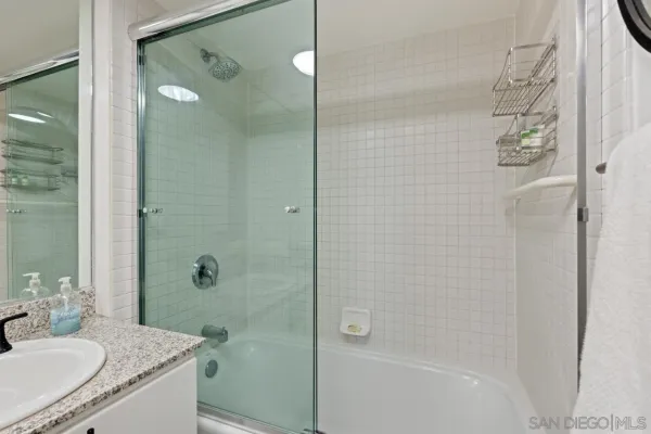 a bathroom with a granite countertop sink a shower and a mirror