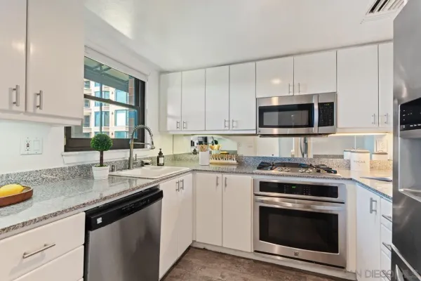 a kitchen with stainless steel appliances granite countertop a sink a stove a microwave and wooden cabinets