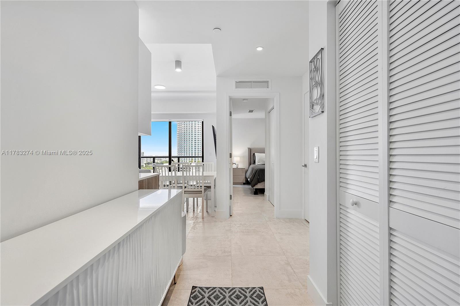 239 Southwest 9th Street, Unit 1704 Miami, FL 33130 - Photo 3 of 36 a large white kitchen with a lot of cabinets and a bed