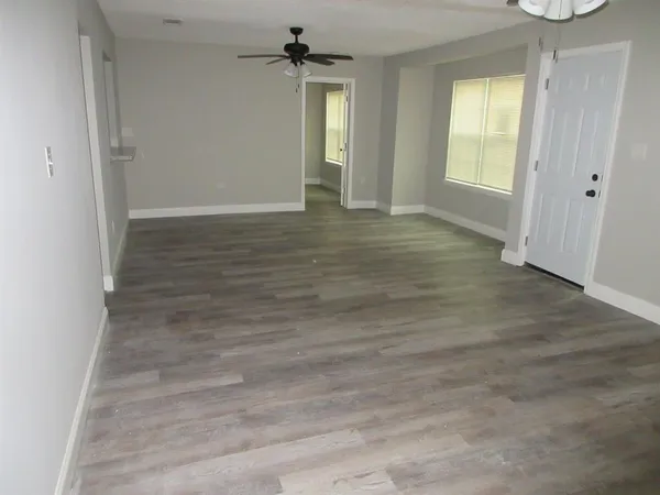 an empty room with wooden floor and windows
