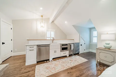 a large white kitchen with stainless steel appliances a stove a sink dishwasher and cabinets with wooden floor