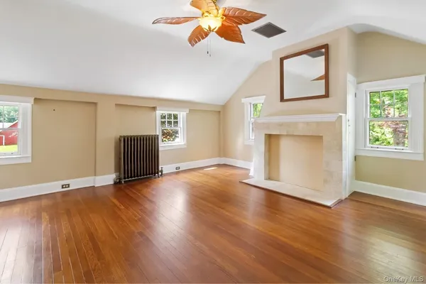 a view of an empty room with window and wooden floor