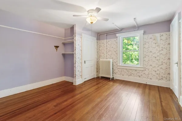 a view of an empty room with a window and wooden floor