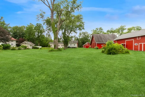 a sign that is sitting in the grass with tress in the background