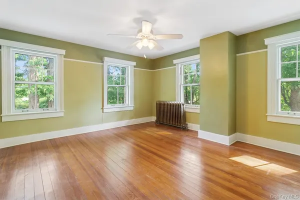 a view of an empty room with a window and wooden floor