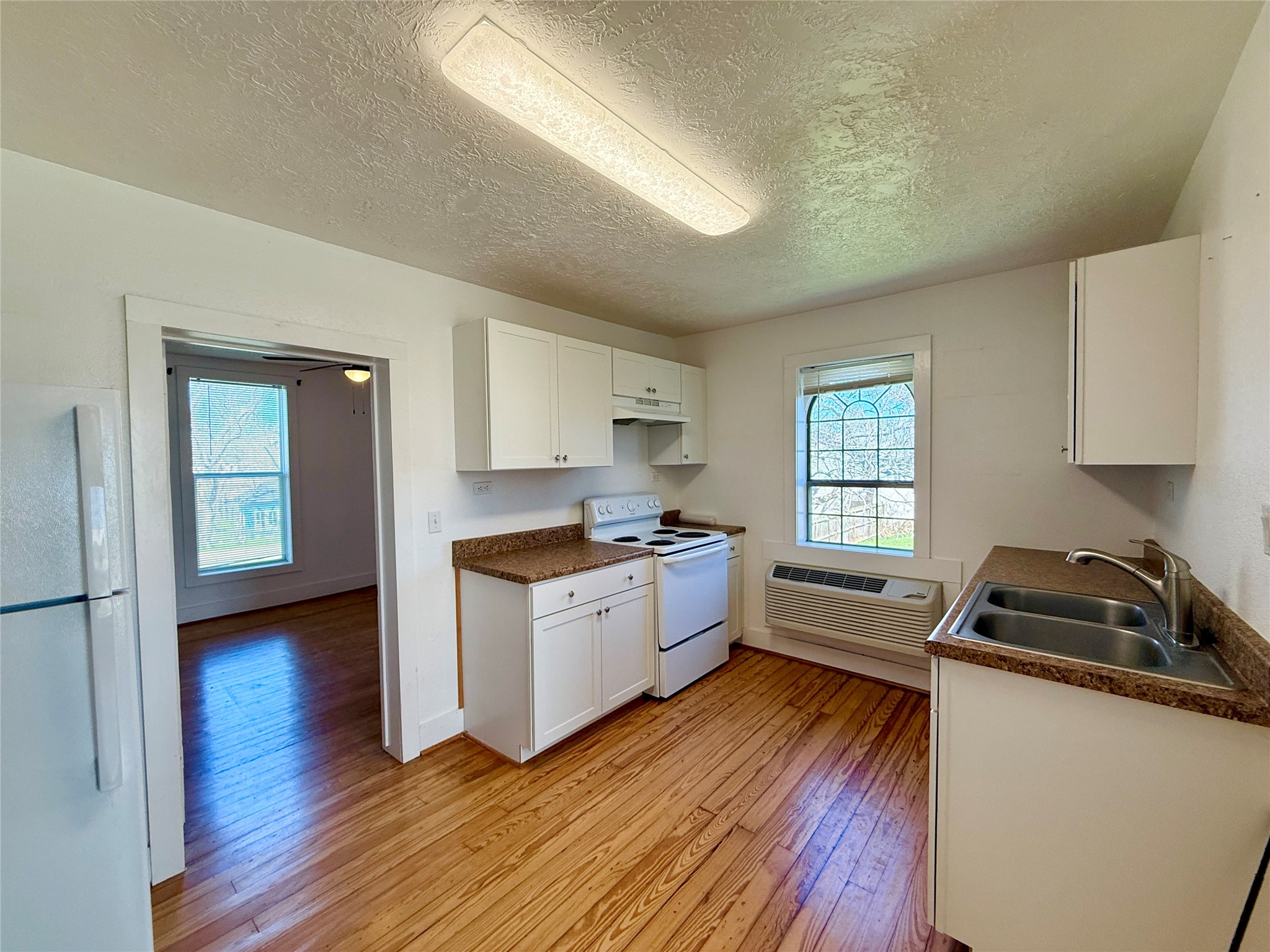 232 South Tesch Street, Unit 236 Bellville, TX 77418 - Photo 4 of 8 a kitchen with granite countertop a sink wooden floor and stove top oven
