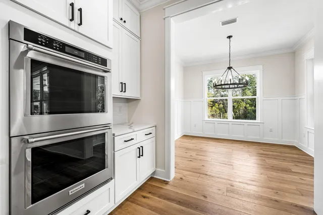 a view of a hallway with wooden floor and a bathroom