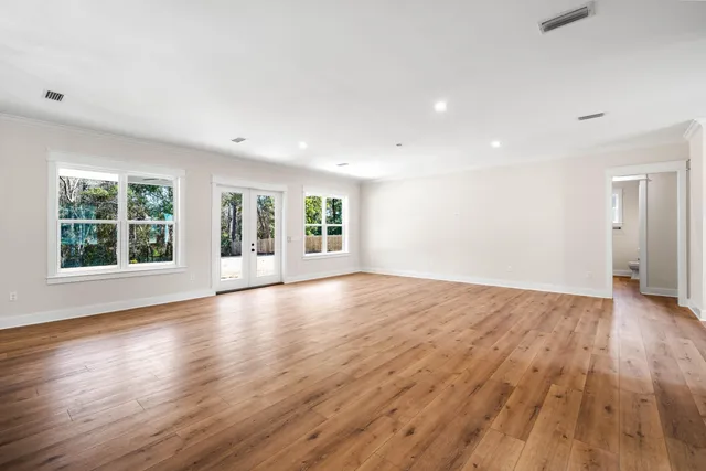 an empty room with wooden floor and windows
