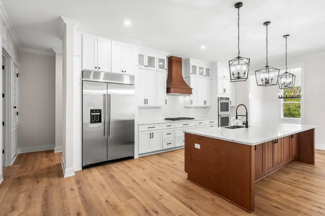 a kitchen with stainless steel appliances granite countertop a stove a sink dishwasher and a refrigerator with wooden floor