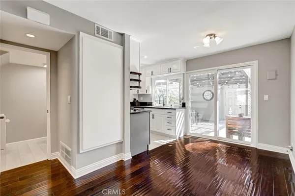 a kitchen with white cabinets and wooden floor