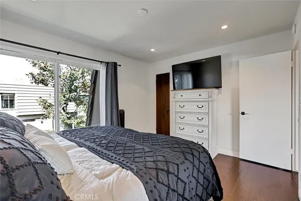 a bedroom with a large bed and a flat tv screen on dresser