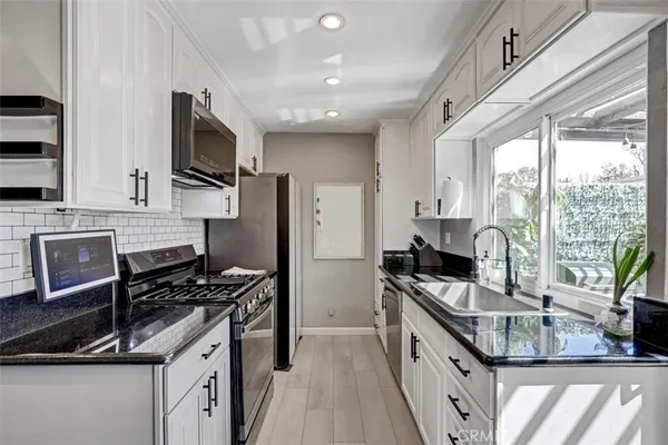 a kitchen with stainless steel appliances granite countertop a stove top oven a sink dishwasher a refrigerator and a microwave