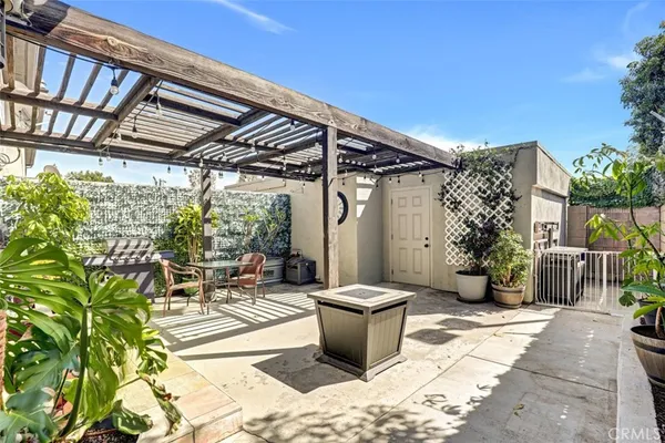 a view of a patio with table and chairs potted plants and floor to ceiling window