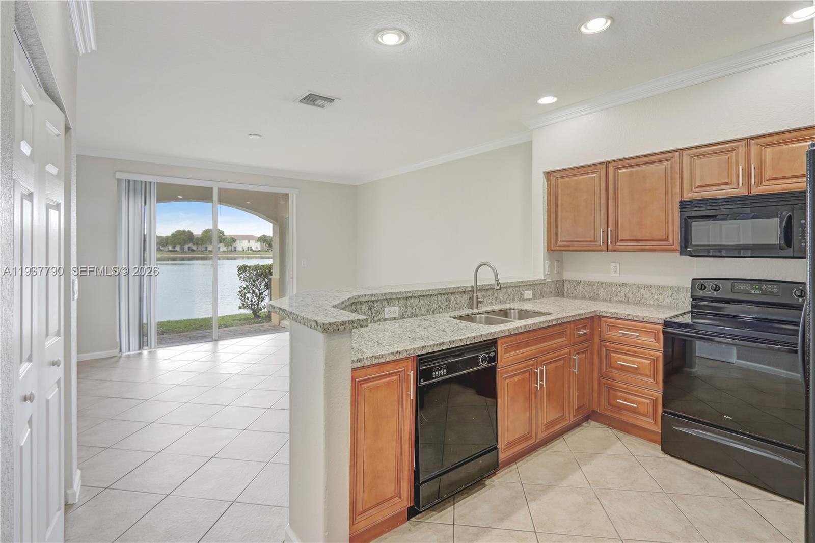 2830 Southwest 83rd Terrace, Unit 101 Miramar, FL 33025 - Photo 6 of 21 a kitchen with kitchen island granite countertop a stove top oven sink and cabinets
