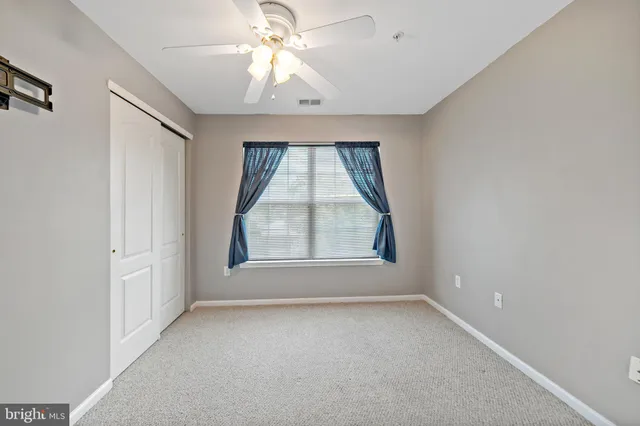 an empty room with a window and a ceiling fan
