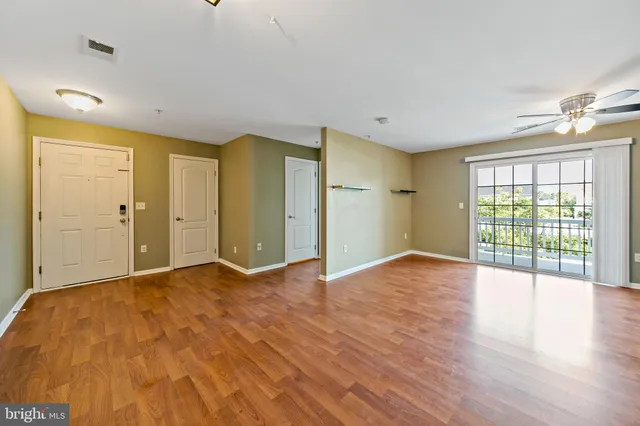 a view of empty room with wooden floor and fan