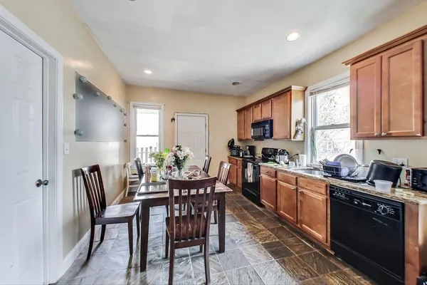 a kitchen with granite countertop stainless steel appliances a table and chairs in it