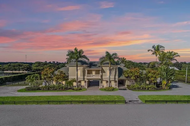a view of a white house with a big yard and a garden