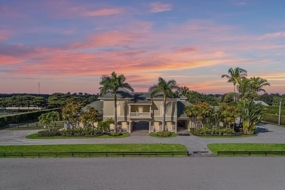4591 S Road Wellington, FL 33414 - Photo 3 of 42 a view of a white house with a big yard and a garden