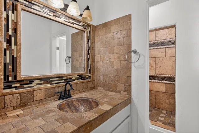 a bathroom with a granite countertop sink a mirror and shower