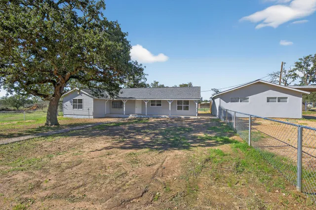 a view of a yard in front of a house with large trees