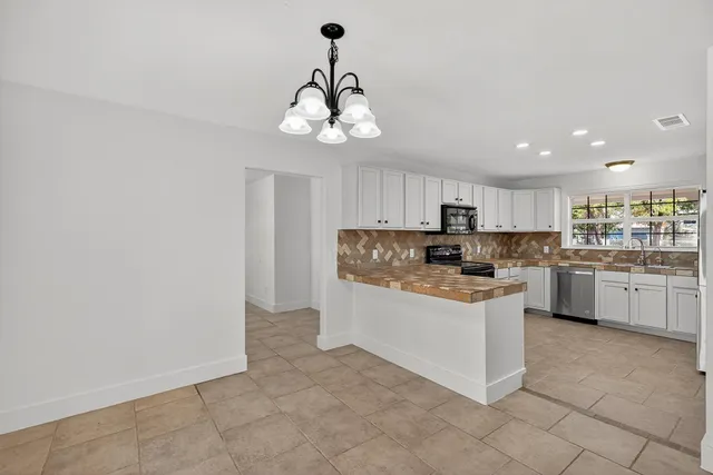 a view of a kitchen with a sink and dishwasher a refrigerator with white cabinets