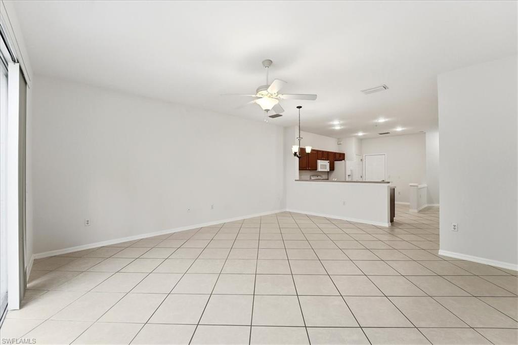 1059 Albany Court, Unit 218 Naples, FL 34105 - Photo 10 of 29 an empty room with a chandelier fan and kitchen view