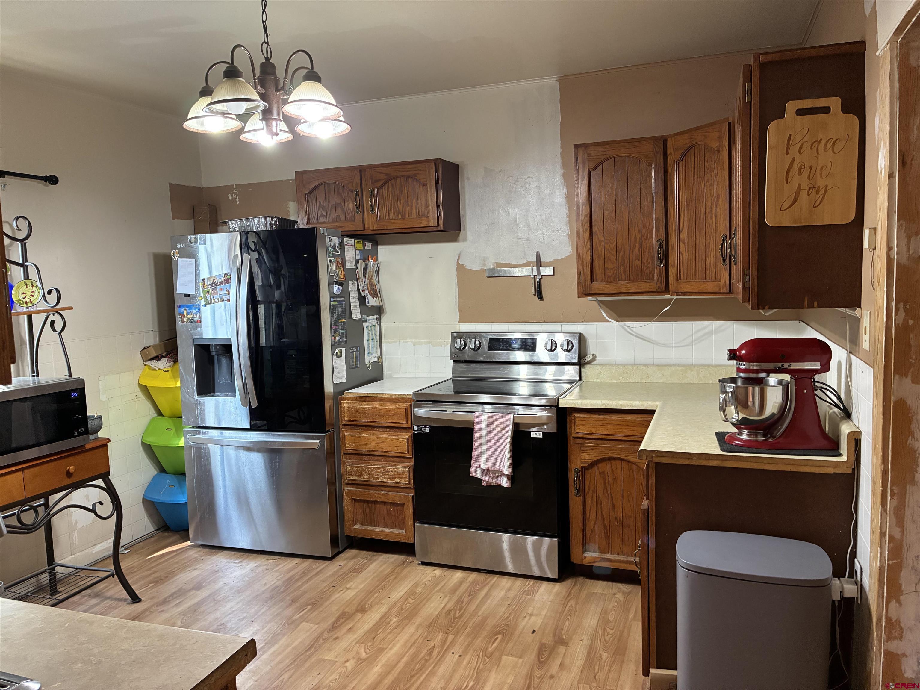 1002 State Avenue Alamosa, CO 81101 - Photo 13 of 19 a kitchen with stainless steel appliances granite countertop a refrigerator a stove top oven a sink dishwasher and white cabinets with wooden floor