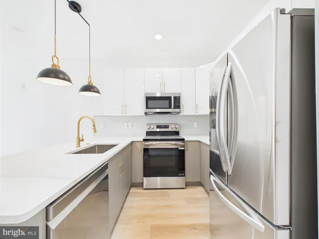 a kitchen with stainless steel appliances granite countertop a sink and a refrigerator