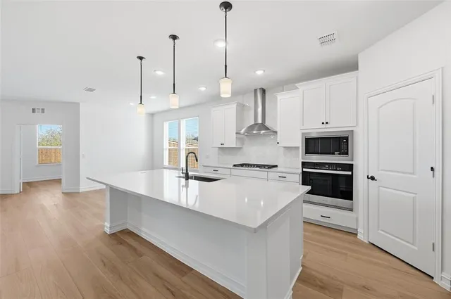 a large kitchen with kitchen island white cabinets and stainless steel appliances