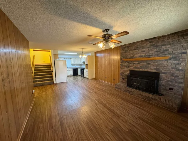 an empty room with wooden floor a fireplace and windows