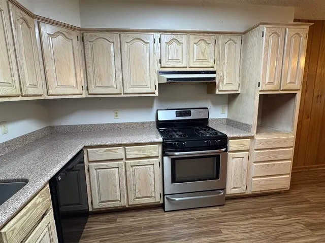 a kitchen with granite countertop white cabinets and stainless steel appliances