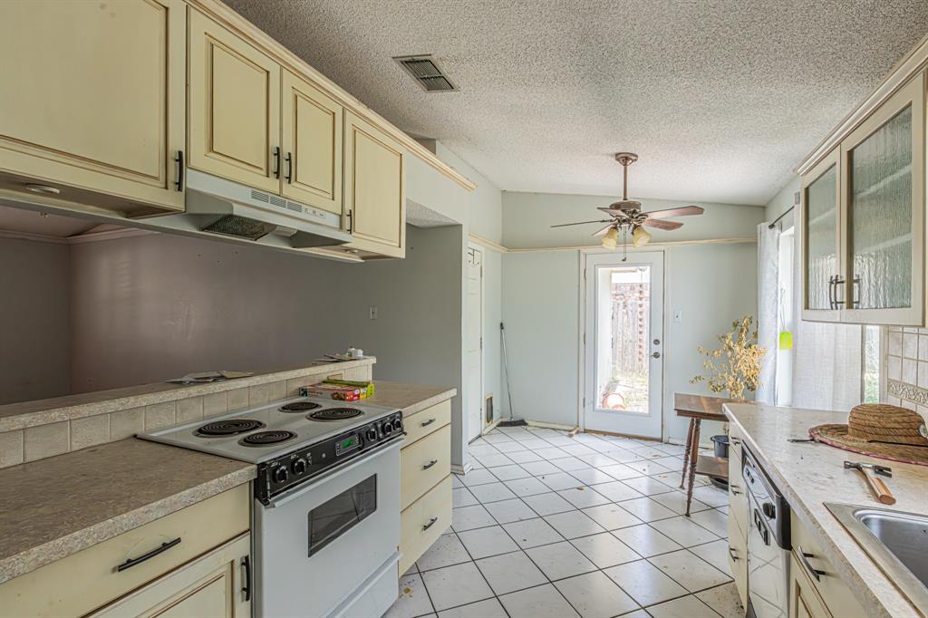 6504 Johnnie Street Watauga, TX 76148 - Photo 12 of 23 Kitchen featuring white tile flooring, painted cabinetry, and a built-in electric range with a ventilation hood