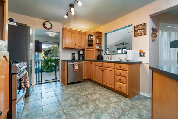a kitchen with stainless steel appliances a sink cabinets and a flat screen tv