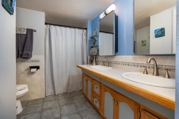 a spacious bathroom with a double vanity sink toilet and shower