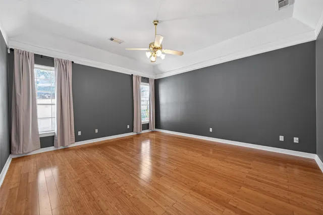 an empty room with windows and ceiling fan