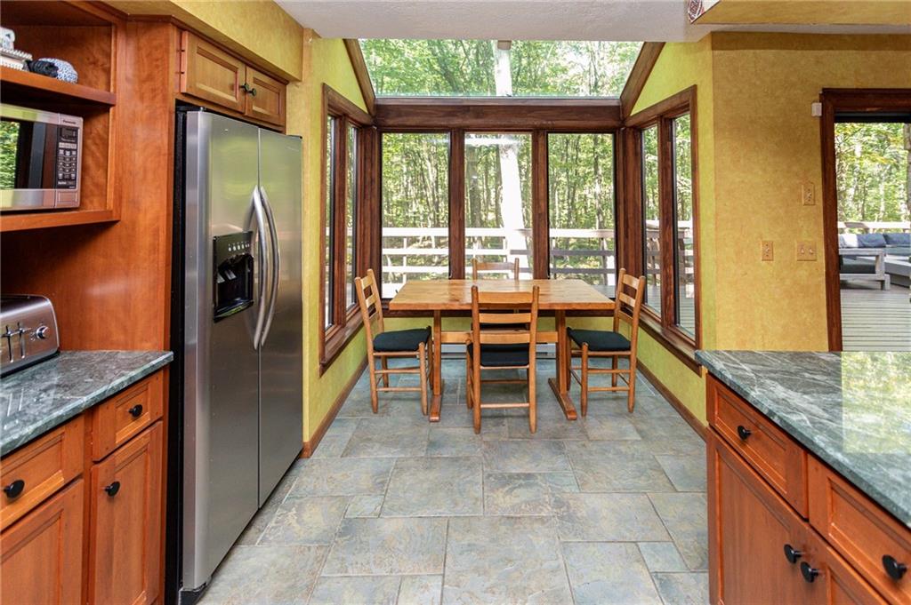 255 Smith School Road Farmington, PA 15437 - Photo 22 of 50 a kitchen with granite countertop a refrigerator stove top oven dining table and chairs