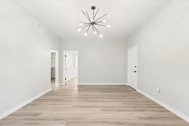 a view of an empty room with wooden floor and a ceiling fan