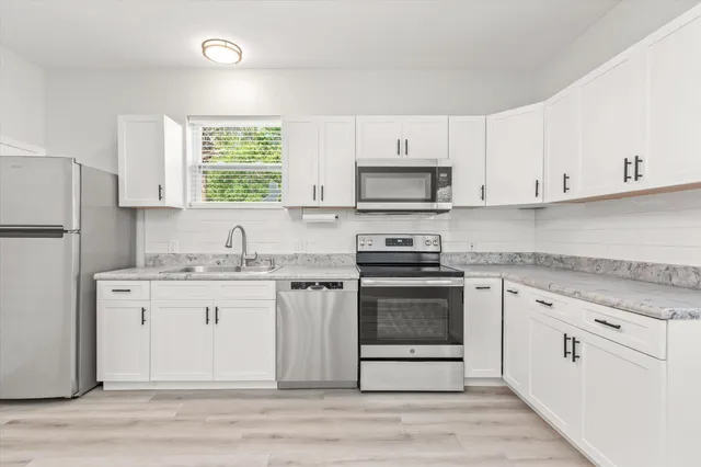 a kitchen with stainless steel appliances granite countertop a stove a sink and a refrigerator